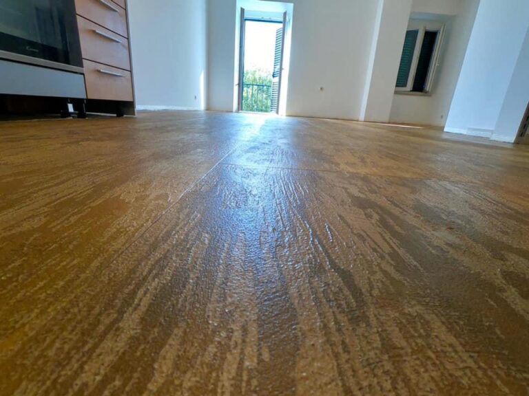 Svetla soba z lesenimi tlemi in odprtimi vrati na balkon.